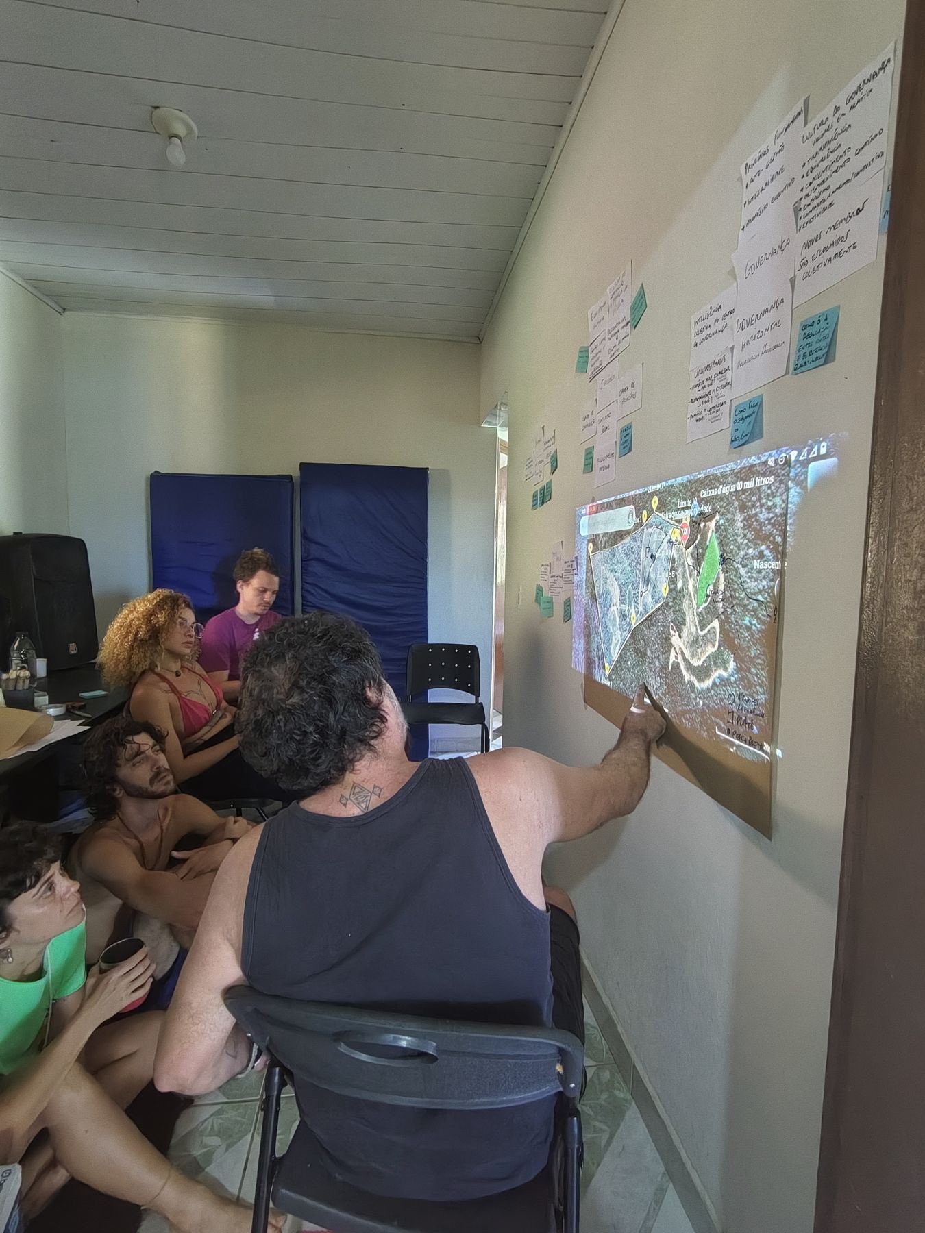 Pessoas reunidas numa sala observando um mapa projetado na parede